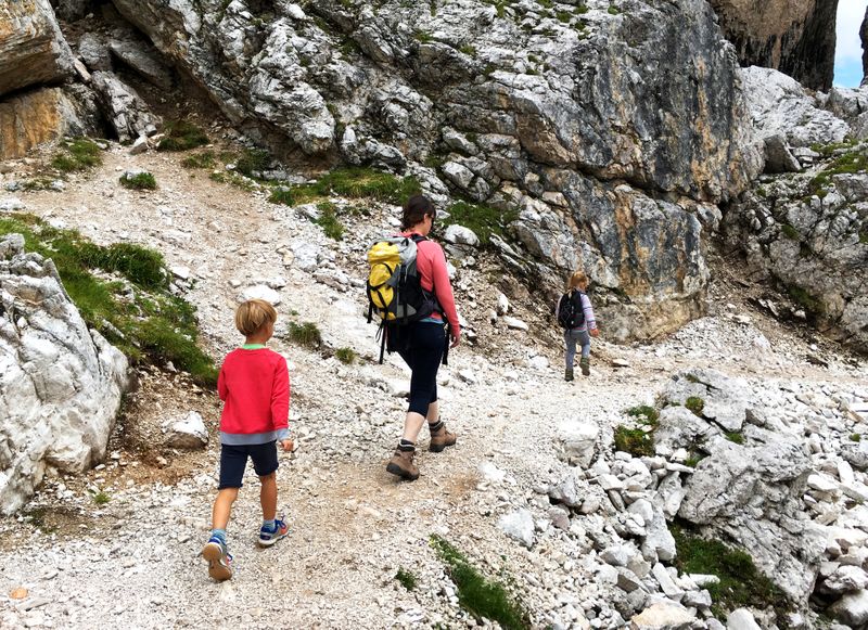 Een familie wandelt over een rotsig bergpad door de Julische Alpen.