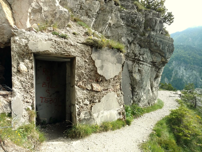 Een deuropening is in de rotsen gehakt langs een wandelpad door de Karawanken.